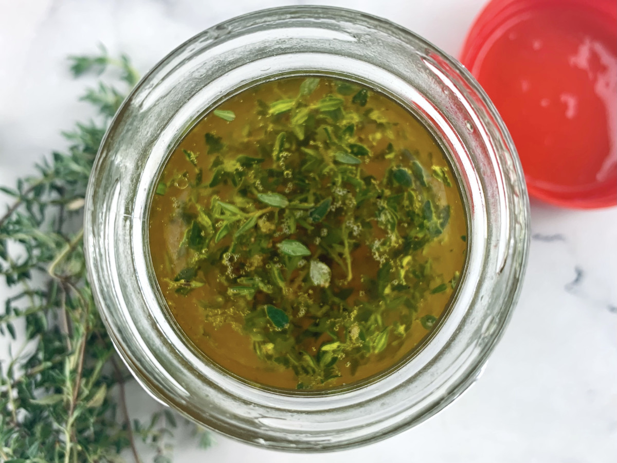 Verjuice vinaigrette ingredients in a glass jar with thyme on the side.