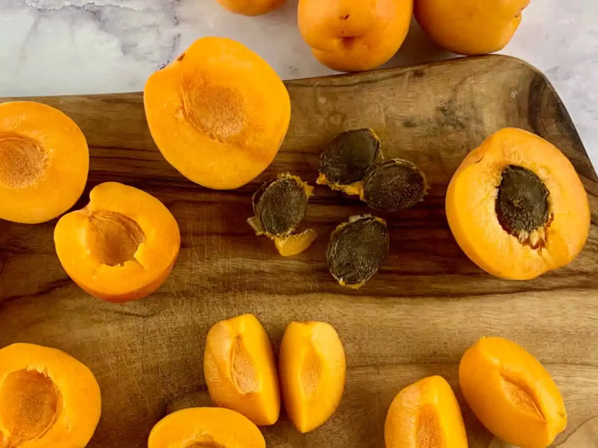 Pitting washed apricots on a wooden board.