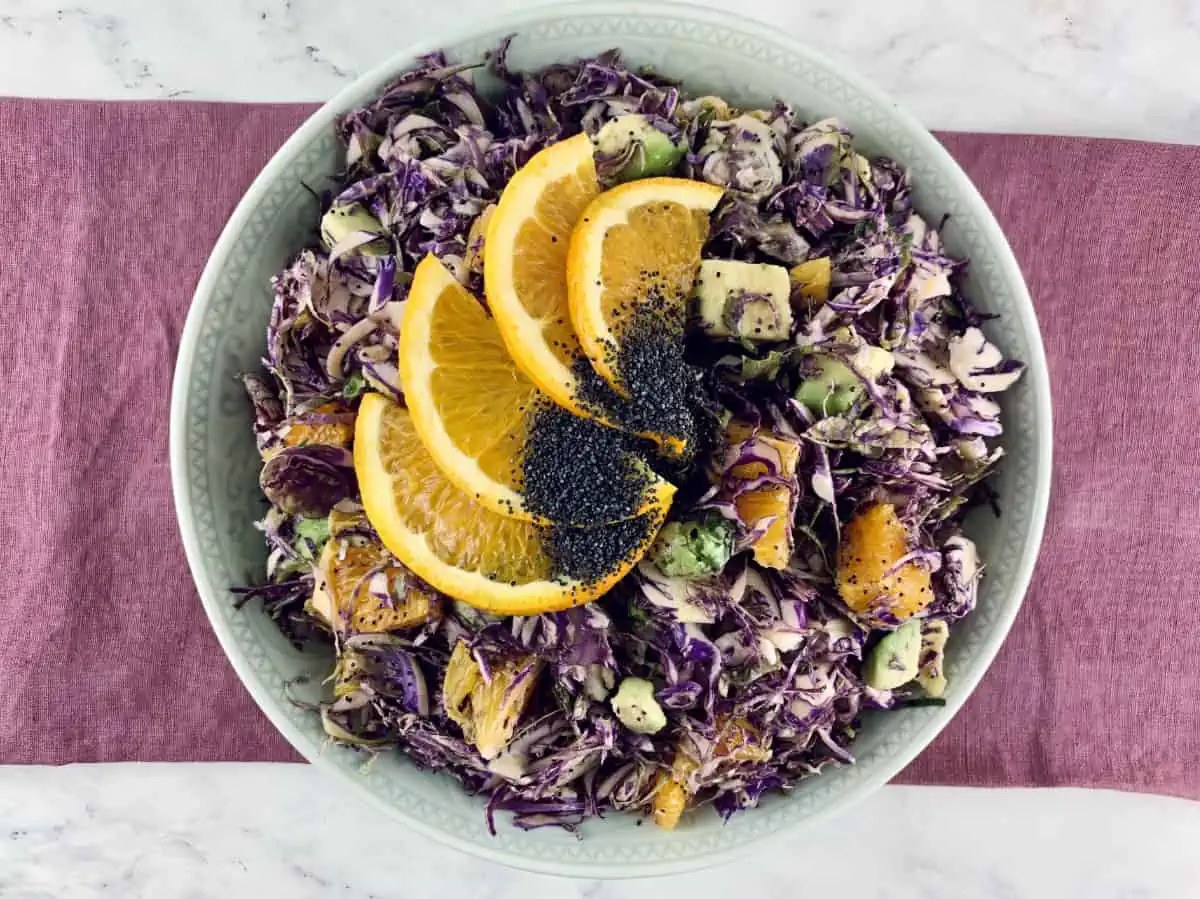 Aerial view of purple Brussel Sprouts with orange slices on top.