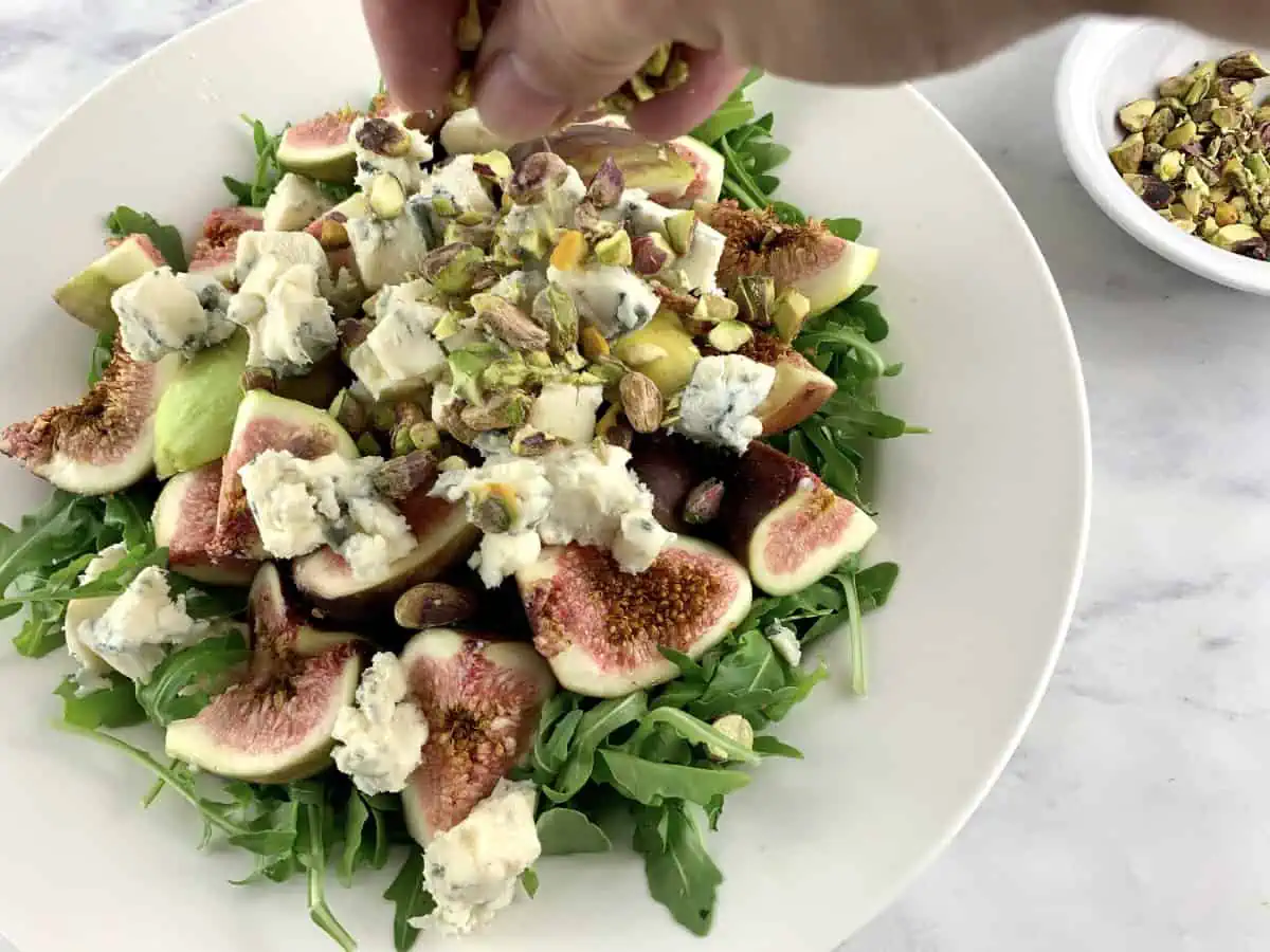 Adding diced gorgonzola to arugula fig salad.