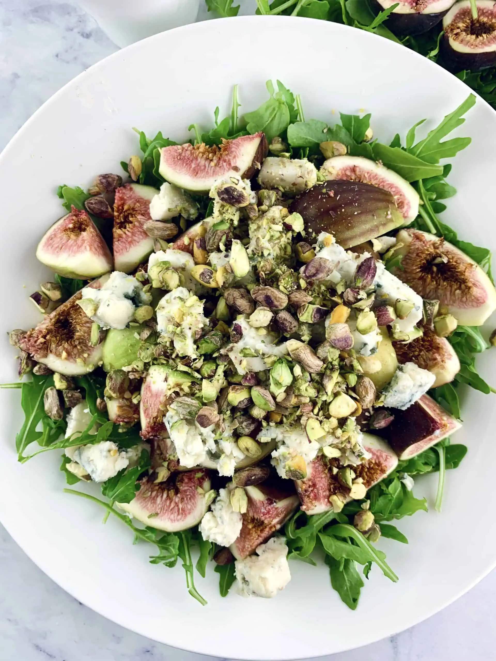 A close up of Arugula fig salad on a white plate.