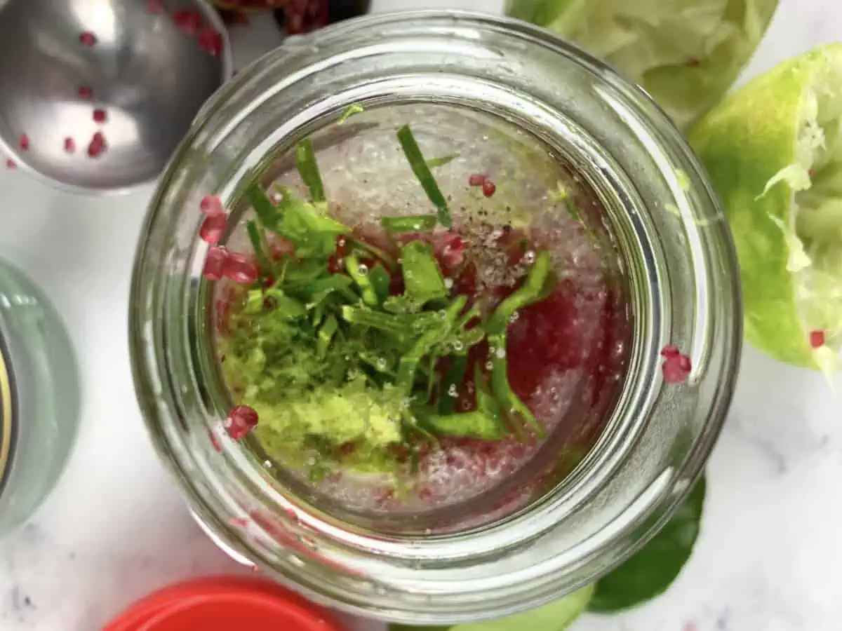 Finger lime dressing ingredients in a jar with ingredients scattered around it.