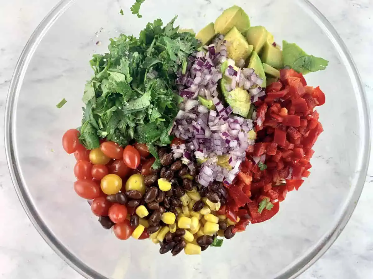 Prepared Mexican avocado salad ingredients in a glass bowl.