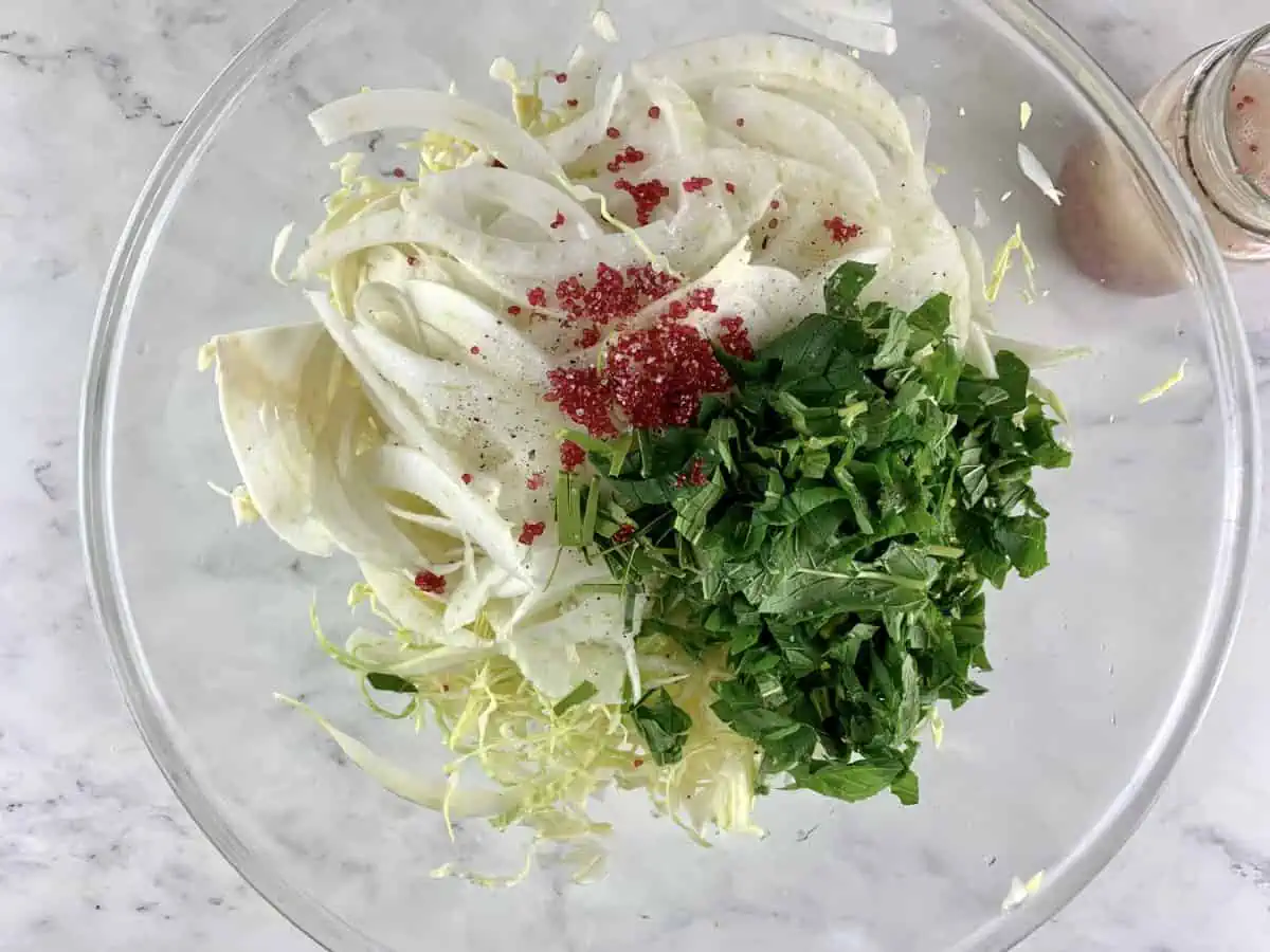 Prepared cabbage fennel slaw ingredients in a glass bowl.