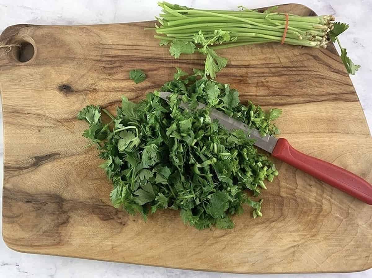 Cutting off parsley stems on a wooden board with a knife.