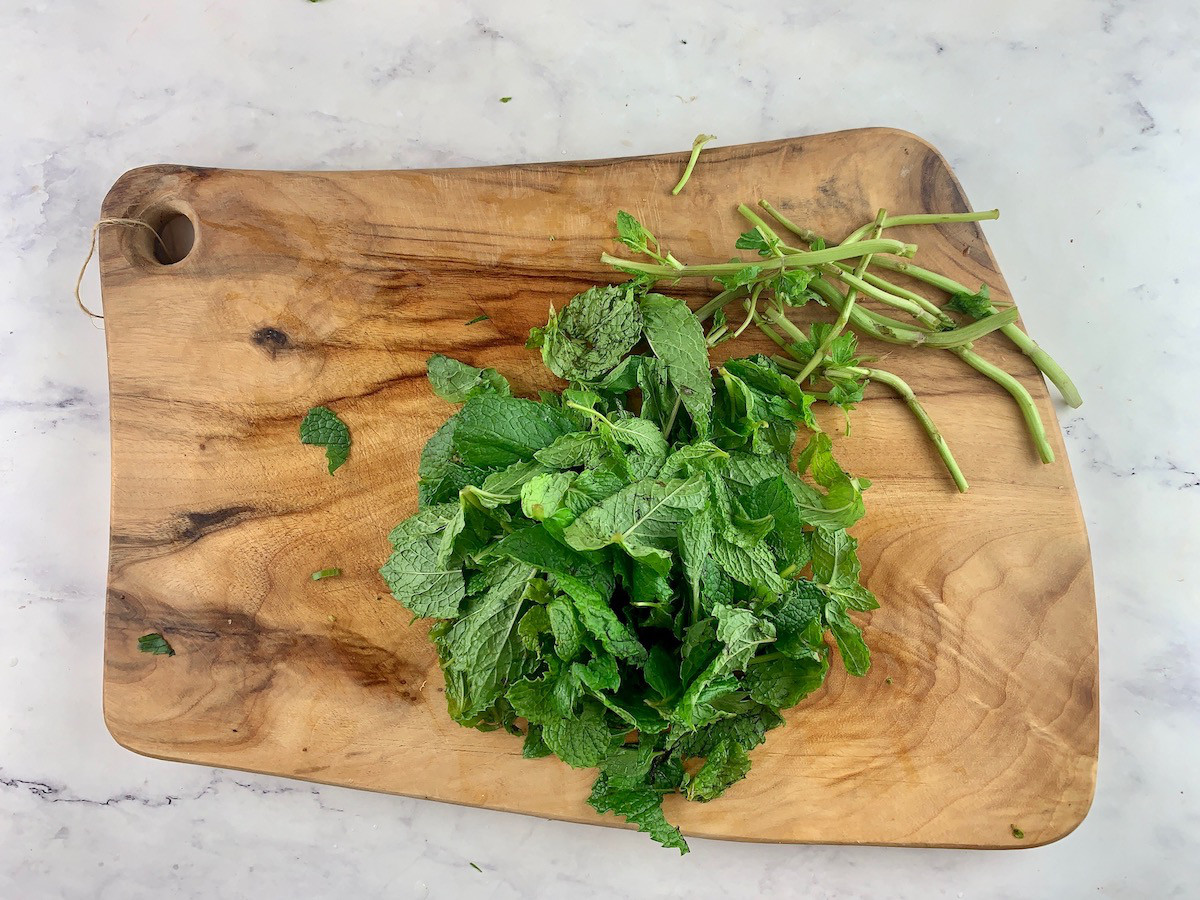 Stripped mint leaves on a wooden board.
