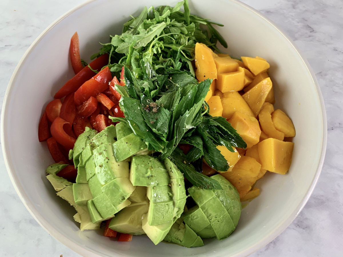 Mango avocado salad with lime dressing ingredients in a white bowl.