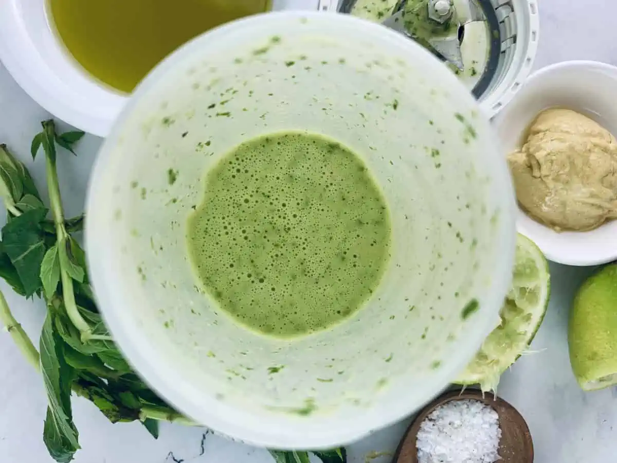 Blitzed mint lime dressing in a blender with ingredients scattered around.