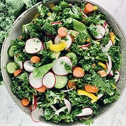 Colourful kale crunch salad in a ceramic bowl with curly kale on the side. a