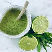 Mint Lime Dressing in a ceramic jug with a spoon with a halved lime and mint leaves.
