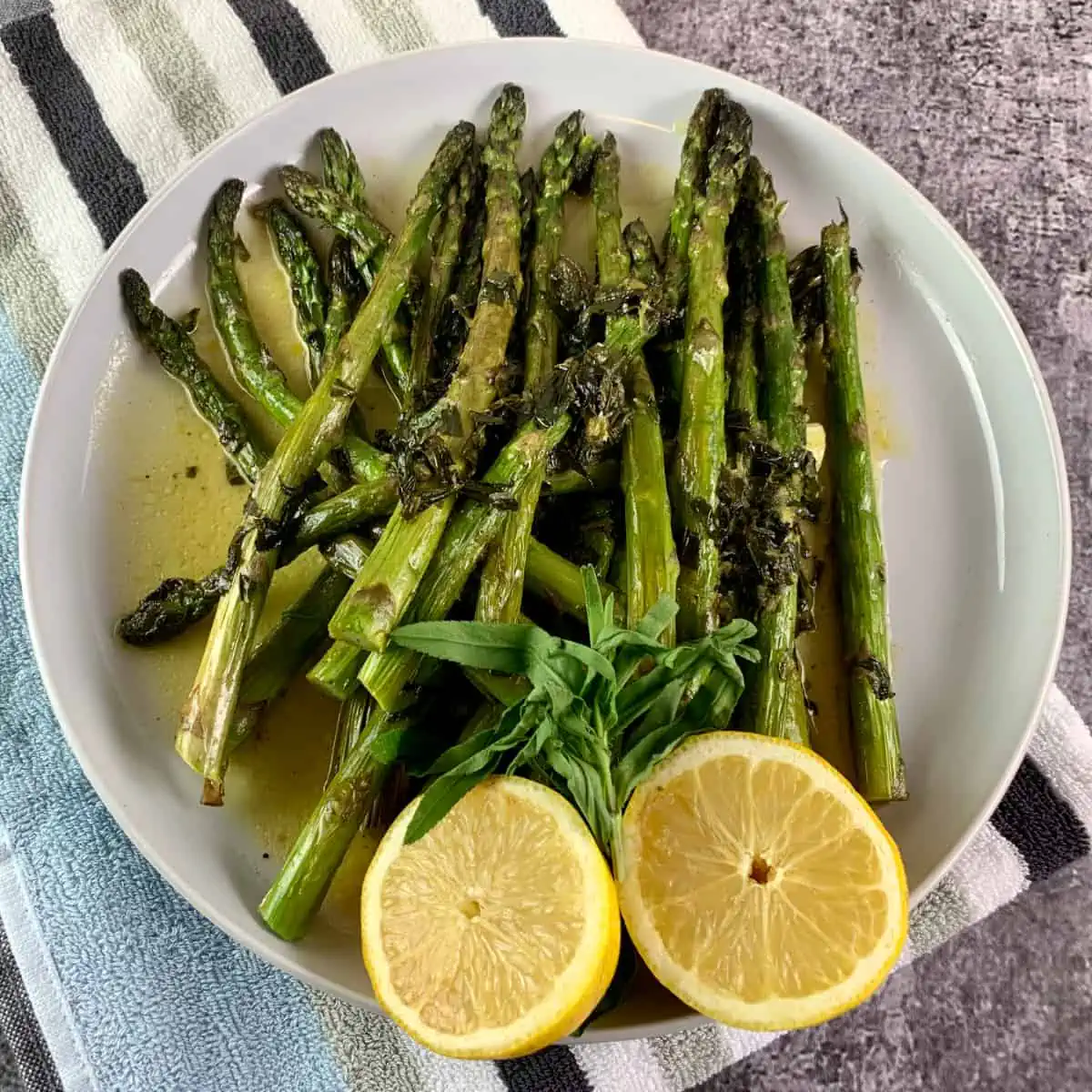 A close-up of oven roasted asparagus with lemon halves. 