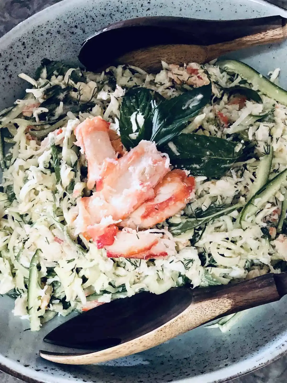 Crab meat salad in a stone-grey bowl with wooden servers.