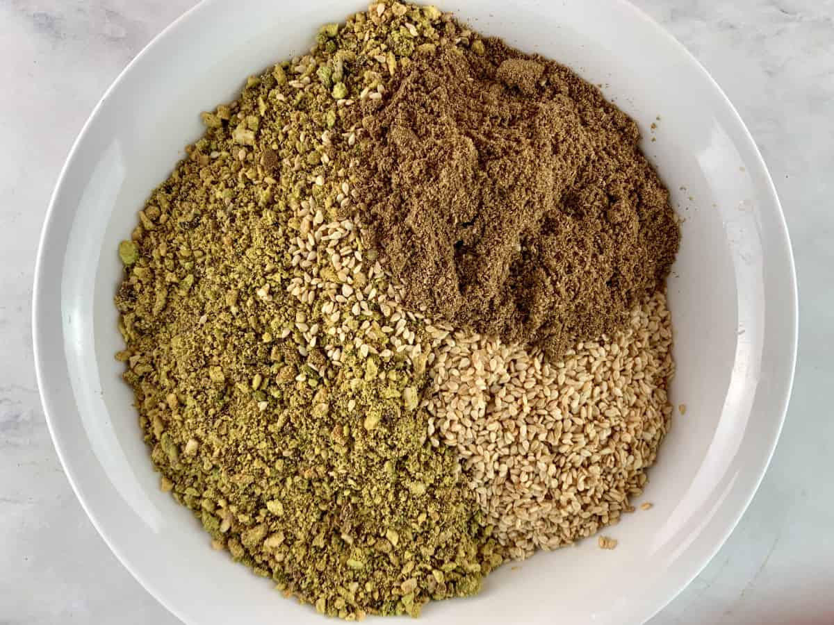 Ground pistachio dukkha ingredients in a white bowl.