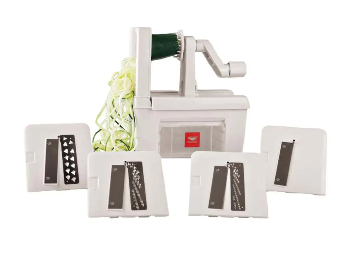Paderno 4-blade spiralizer in the background with zuchini spirals and the 4 different blades in the front.