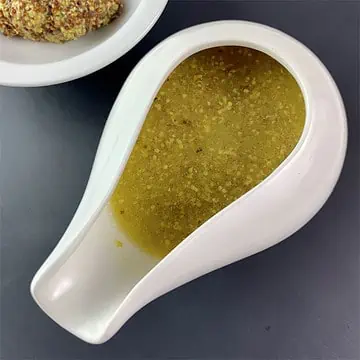 Honey mustard vinaigrette in a small white jug with wholegrain mustard on the side.