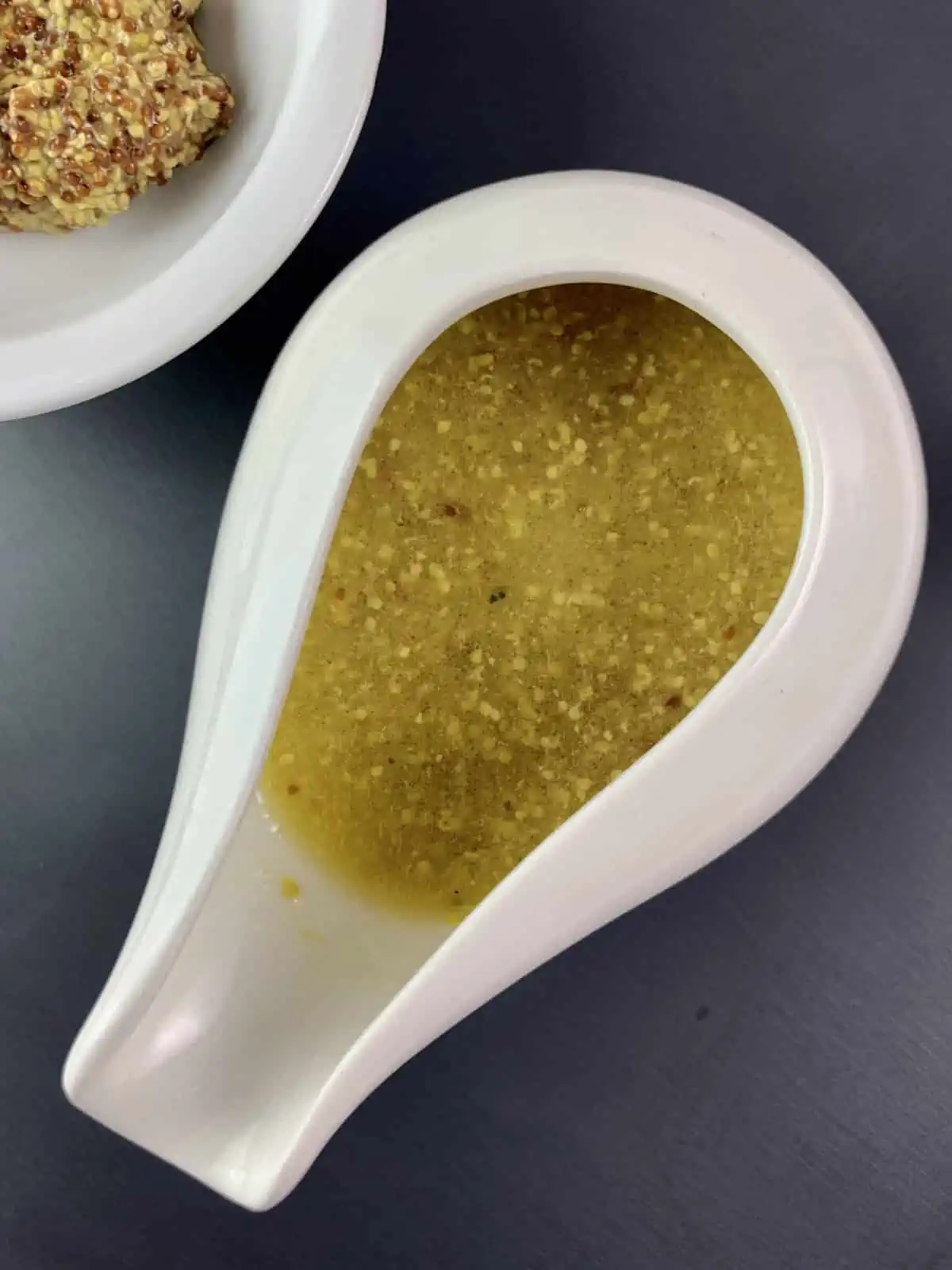 Honey mustard vinaigrette in a small white jug with wholegrain mustard on the side.
