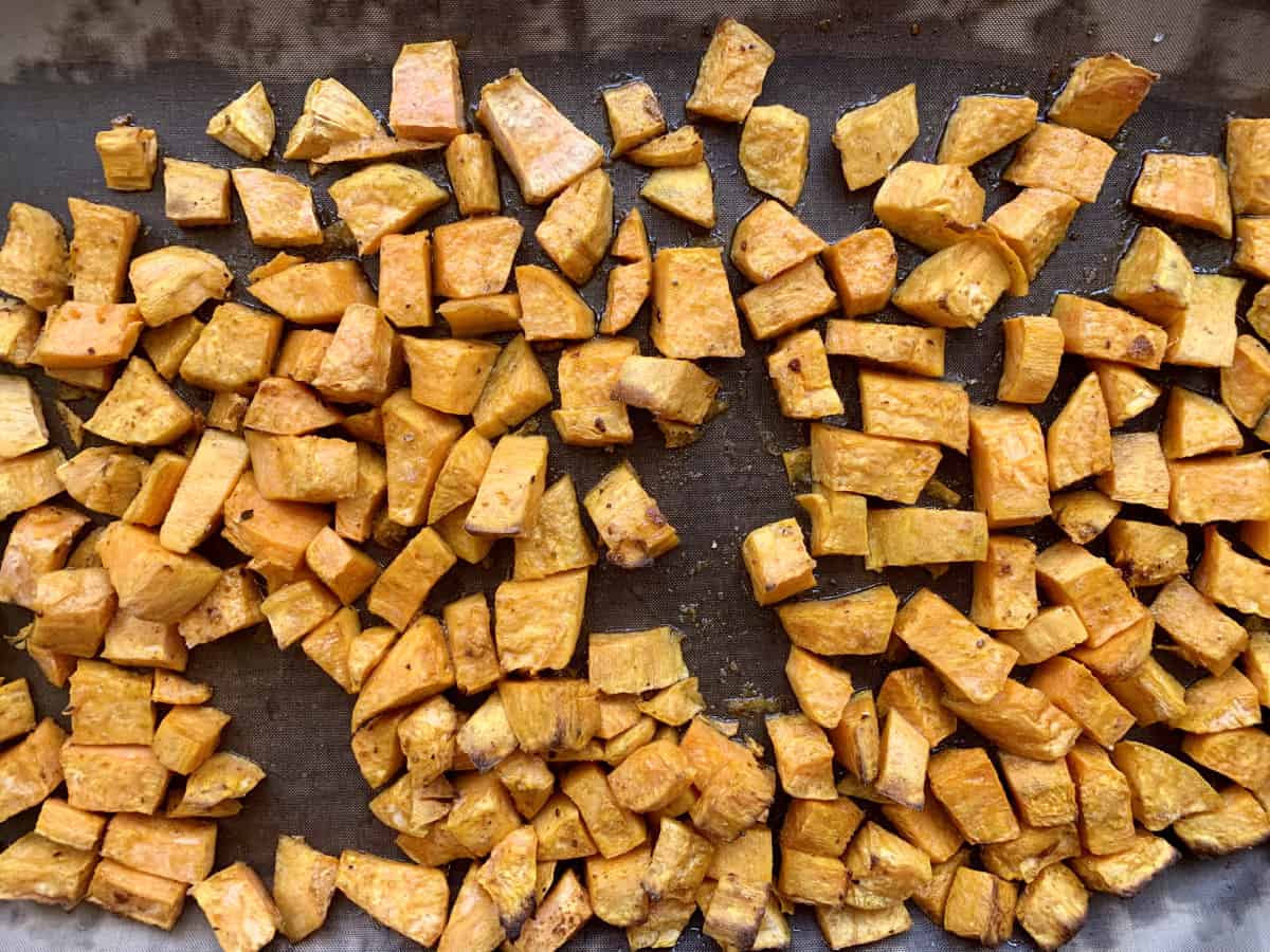 Roasted, diced sweet potatoes in a pan with oil and spices.